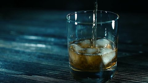 whiskey on the rocks poured from a bottle - alcohol, bar Whiskey pouring into a glass with ice