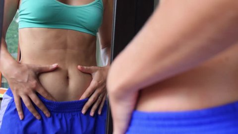 Girl Looking at Herself in Mirror Touching Stomach Fat 