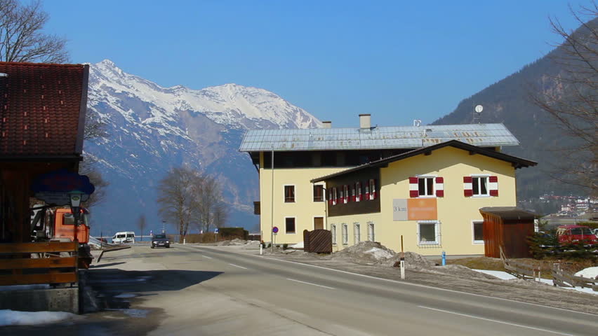 Car passing hotel and filling station, snowy mountains and blue sky background