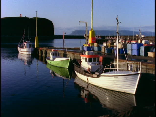 Small fishing boats float beside a dock.