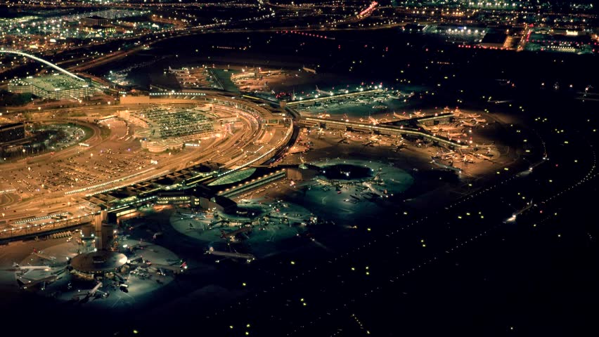 helicopter establishing shot of airplanes parking at international airport terminal at night. global business background