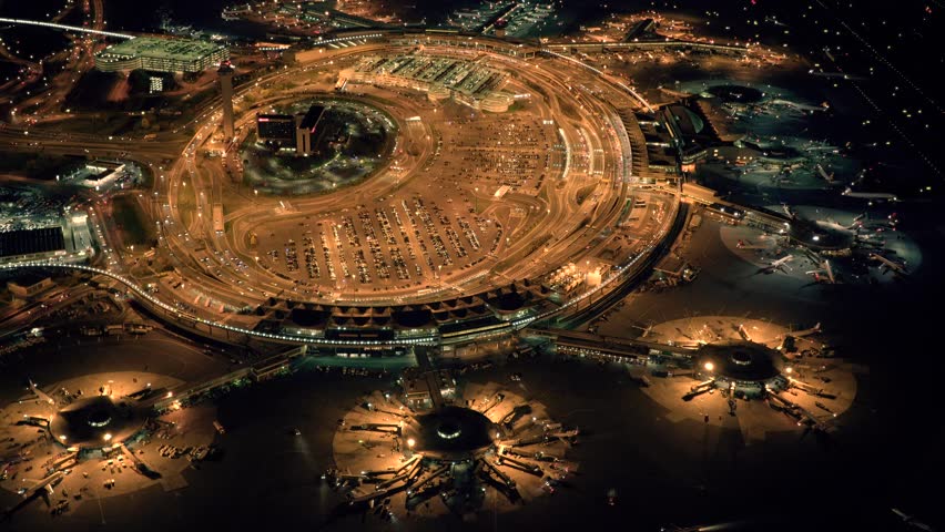 helicopter establishing shot of airplanes parking at international airport terminal at night. global business background