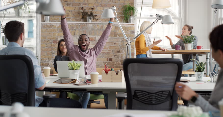 Businessman with arms raised celebrating success watching sport victory on laptop diverse people group clapping expressing excitement in office