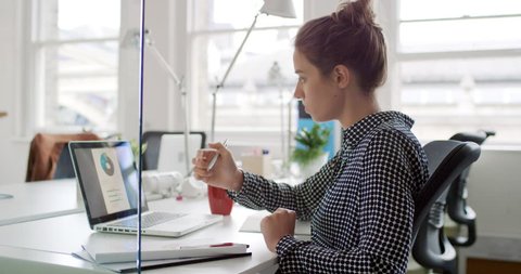 Young business woman working at shared desk in trendy hipster start up office using big data on laptop computer Stock Video
