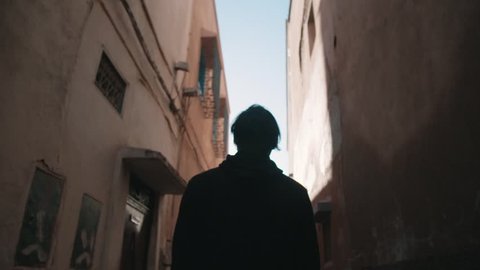 Figure walking through a tight Moroccan alley way 
