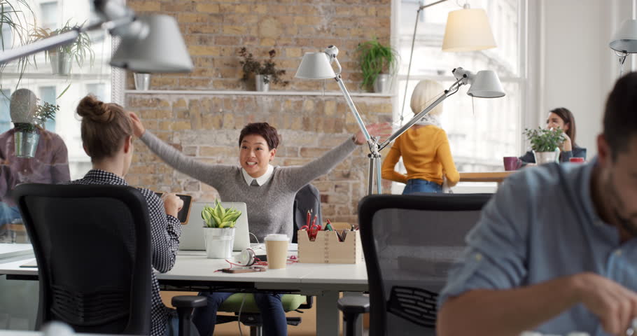 Business woman with arms raised celebrating success watching sport victory on laptop diverse people group clapping expressing excitement in office