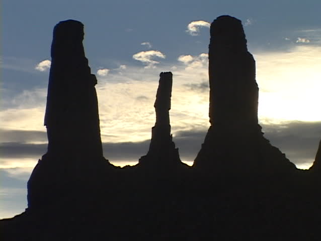 The Three Sisters stand in silhouette in Monument Valley, Utah.