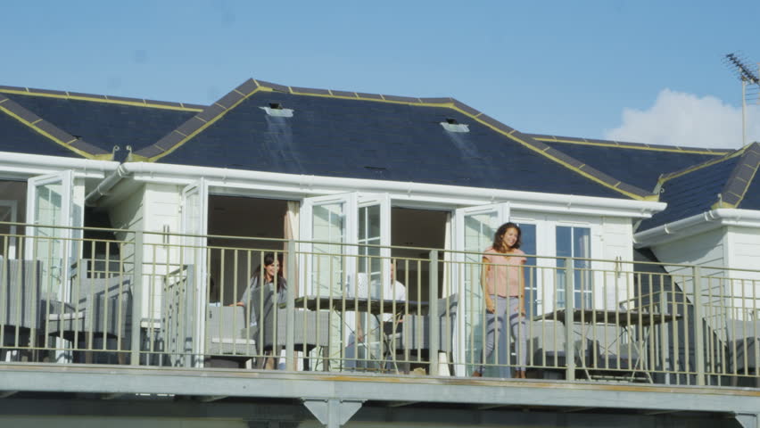 4k / Ultra HD version Happy attractive young group of friends on vacation go out on the balcony to look at the view. Shot on RED Epic