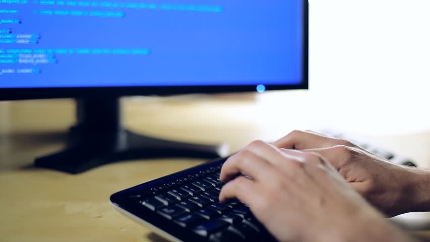 Hacker or programmer typing on computer keyboard. Man writing or programming code in dark room with back light. People working in office hands closeup. Technology concept. Shot with Canon 5DMkII