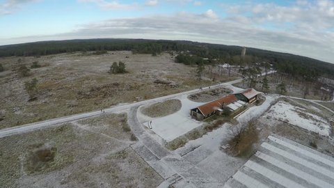 Aerial drone UAV flying over abandoned barracks heath landscape covered in some snow nature reserve flying machine turning hard right then steady flying straight towards concrete water tower 4k
