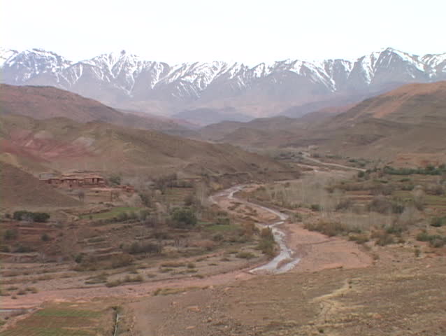 Snow capped mountains tower over rugged valleys.