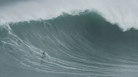 NAZARE, PORTUGAL - NOVEMBER 1, 2015: Big wave surfers ride huge waves. Nazare, an iconic surfing spot, is the home to some of the largest waves on earth.