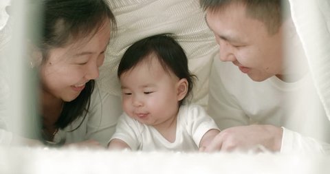 young Asian family with a 6 month child on the bed