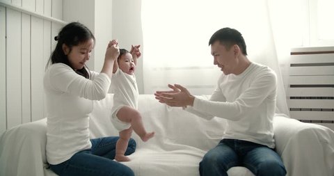 young Asian family playing with 6 month old baby, slow motion