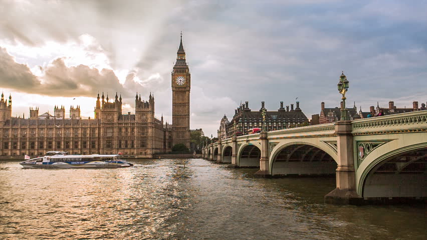 Sunset at Big Ben in England, UKRed buses and boats pass over Westminster Bridge in foreground of London's historical and iconic landmark