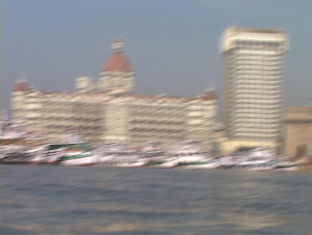 A point of view from a small boat entering the harbor in Bombay, India with the Taj Mahal Hotel and Gateway Arch in background.