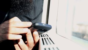 close up of man hands chatting with his smartphone traveling on train in a sunny day