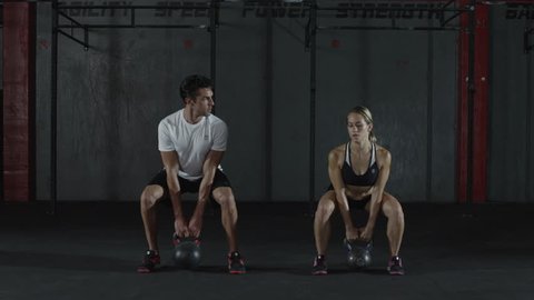 A man and woman doing kettle bell exercising and lifts, squats - kettlebell - fitness / crossfit / exercise / workout