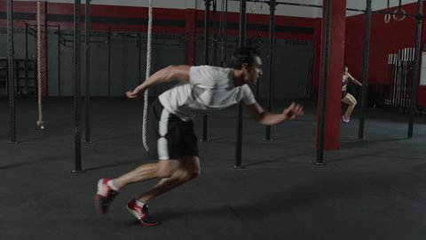 A man sprinting, touching the ground, and changing direction in a slow motion tracking shot - fitness / crossfit / exercise / workout / runner / running