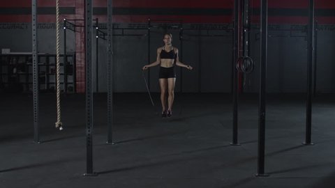 Second take of dollying into woman jump roping in slow motion inside of a gym - fitness / crossfit / exercise / workout