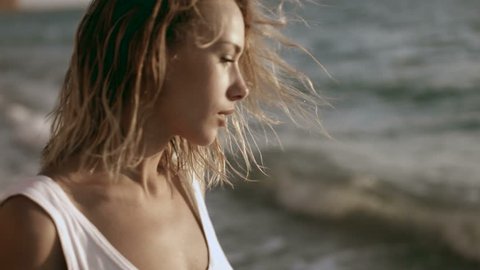 Sexy young woman in a white T-shirt on a naked body next to the sea in the evening