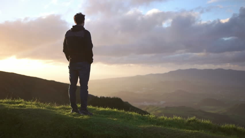 Young caucasian man looking down from the mountaine towards the ocean