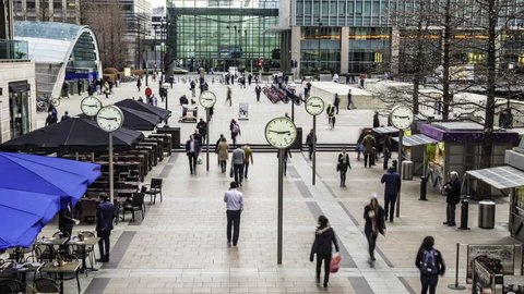 Time lapse view of people rushing from work with several clocks in the docklands financial centre in London