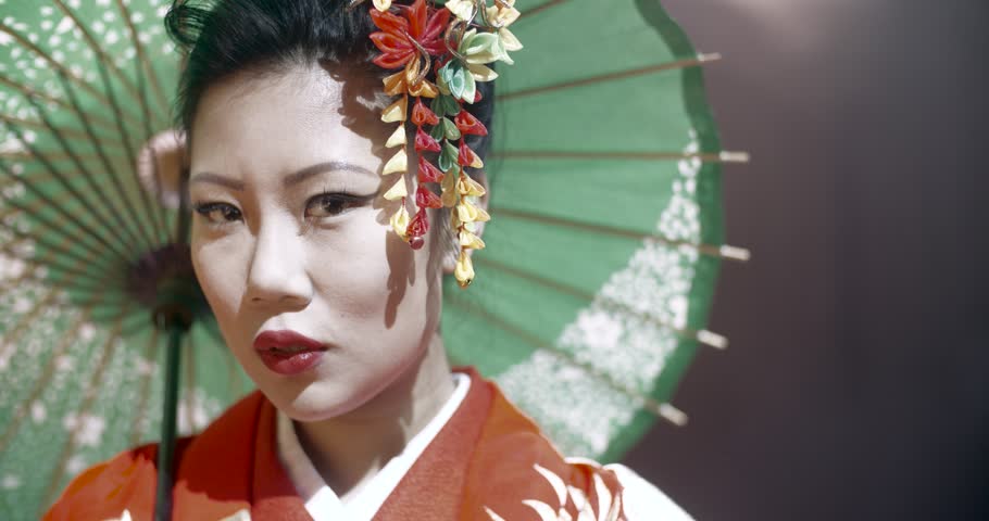 beautiful Japanese geisha posing for the camera with an umbrella on stage, epic slow motion, smoke and dark background