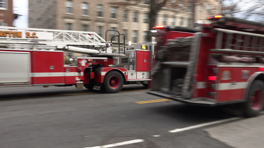WASHINGTON, DC - JAN. 2016: DC Fire trucks arrive, sirens, one stops lets other turn corner.  Fire truck crews include EMTs, as EMS is part of fire department in DC
