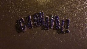 Sparkling glitter confetti falling on Carnaval! message on textured gold background 