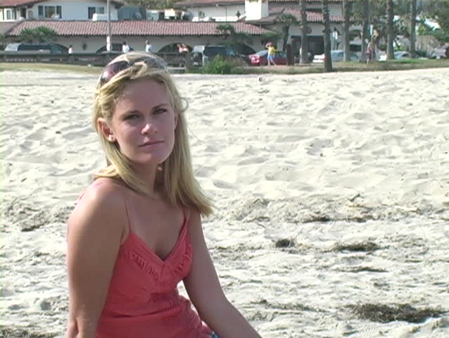 Young woman sitting on the beach staring at the camera.