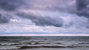 Waves roll in and crash on the Ohio coast of Lake Erie under a stormy cloudy sky on a blustery, windy day.