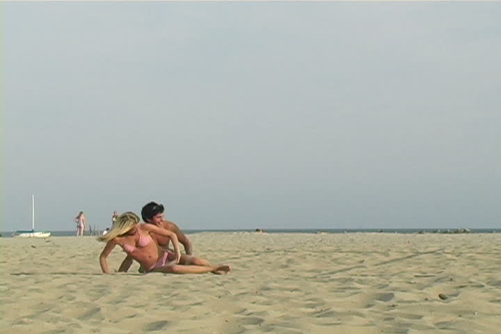 Young couple plays in the sand.
