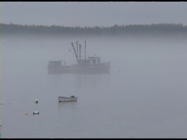 Medium shot of fishing boats sitting in a foggy harbor in Jonesport, Maine.