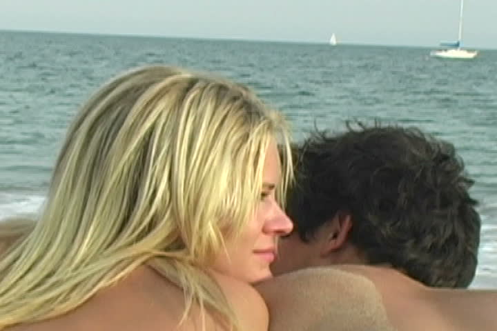 Couple lying on the beach talking as camera zooms-out.