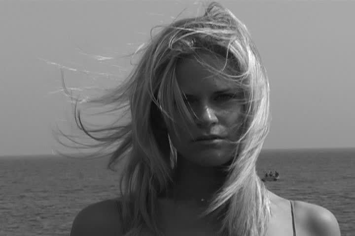 A beautiful woman staring at the camera as wind blows her hair.