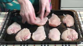 Woman prepares chicken on a baking sheet