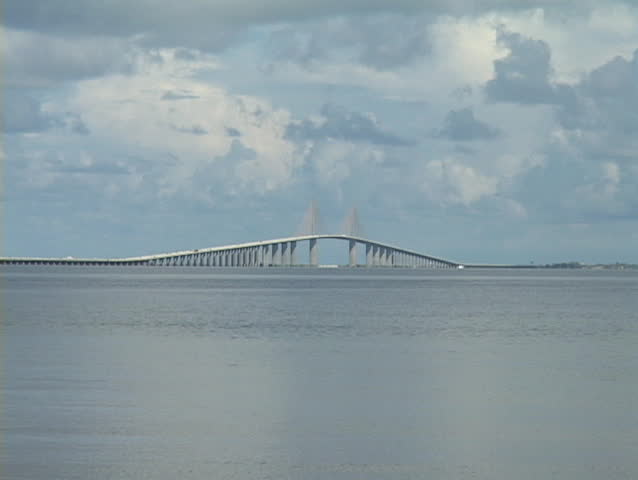 Vacationers walk on a beach under a cloudy sky.