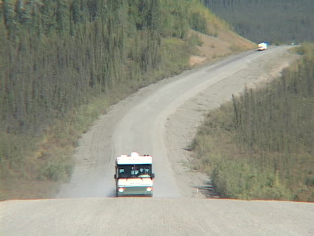 A motor home travels down a dirt road in Alaska.