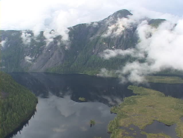 An aerial of a float plane flying over Alaskan fjords.