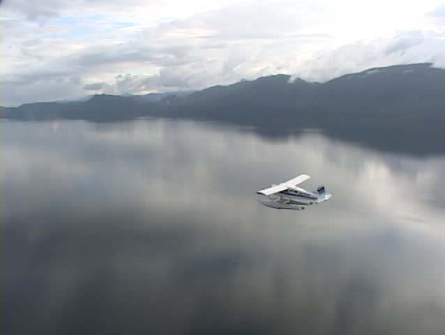 An aerial of a float plane flying over Alaskan fjords.