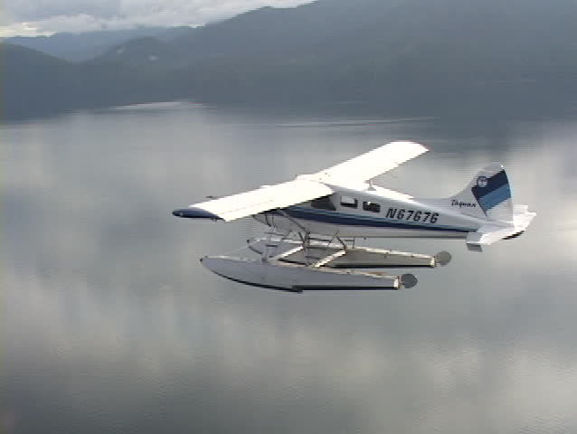 An aerial of a float plane flying over Alaskan fjords.