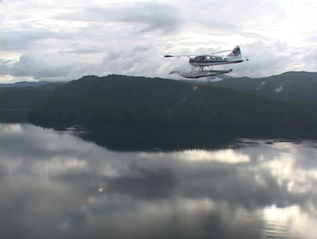 An aerial of a float plane flying over Alaskan fjords.