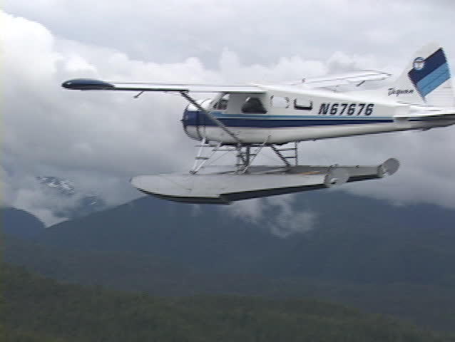 An aerial of a float plane flying over Alaskan fjords.
