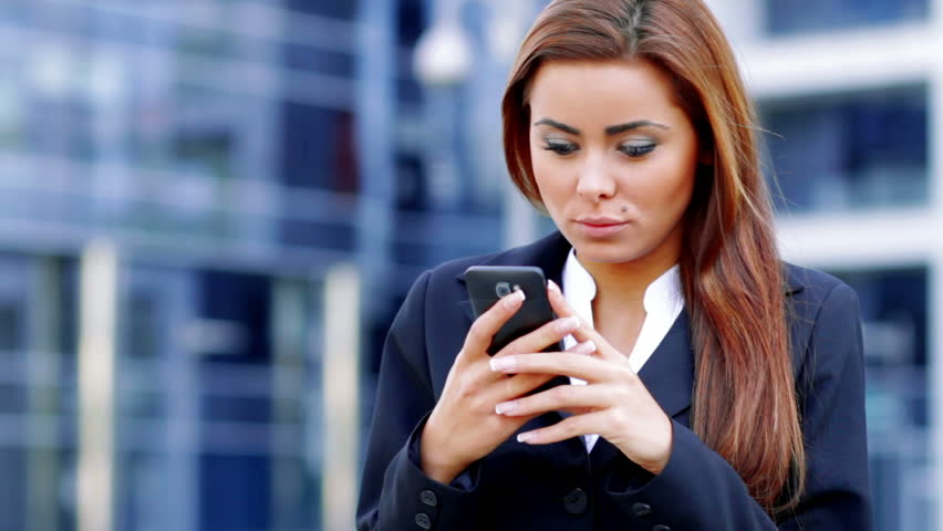 A beautiful business woman using mobile phone outside office building