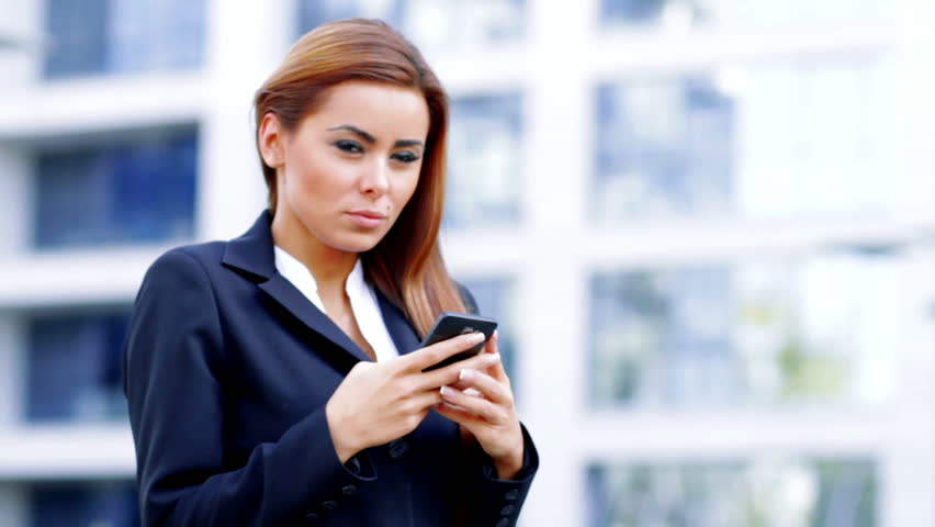 A beautiful business woman using mobile phone outside office building