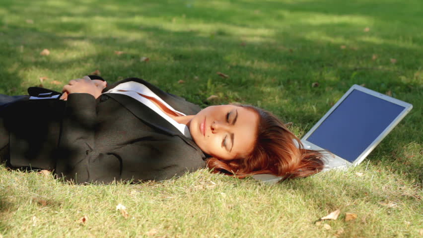 Beautiful business woman relaxing on grass with laptop