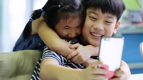 Little asian boy and girl take a photo with cell phone