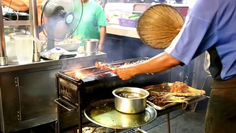 Man barbecuing satay over huge flame, popular food in Malaysia, Indonesia and Thailand. 
