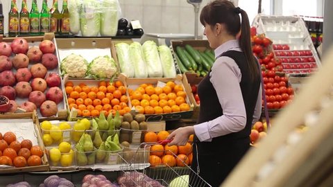 Woman selecting fruit at market and adds to cart, rear view